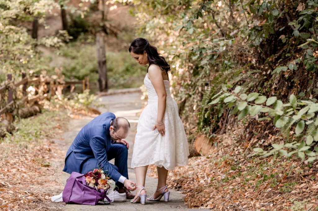 Groom adjusting bride's shoe