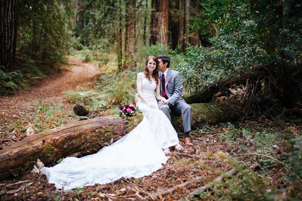 Newly married couple sitting on a redwood log.