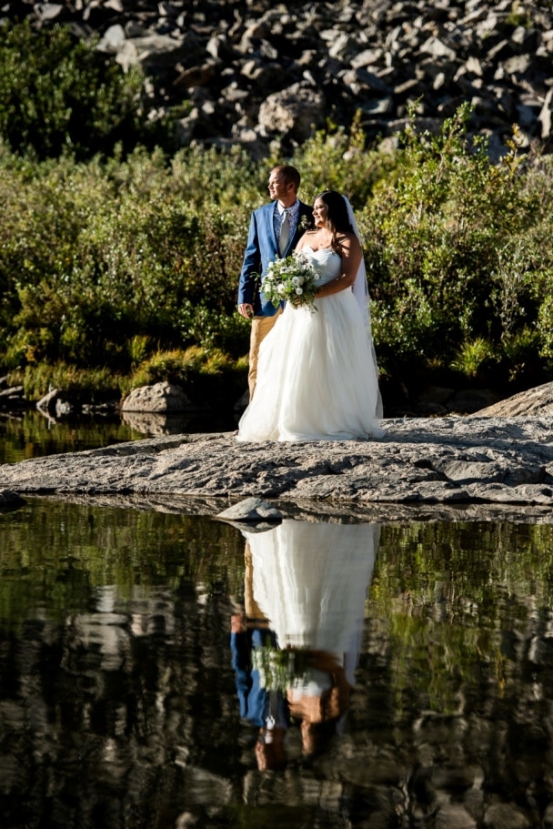 bride and groom on the shores of the mountain lake