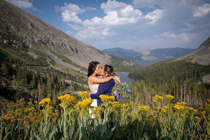 two brides kissing in a field of wildflowers