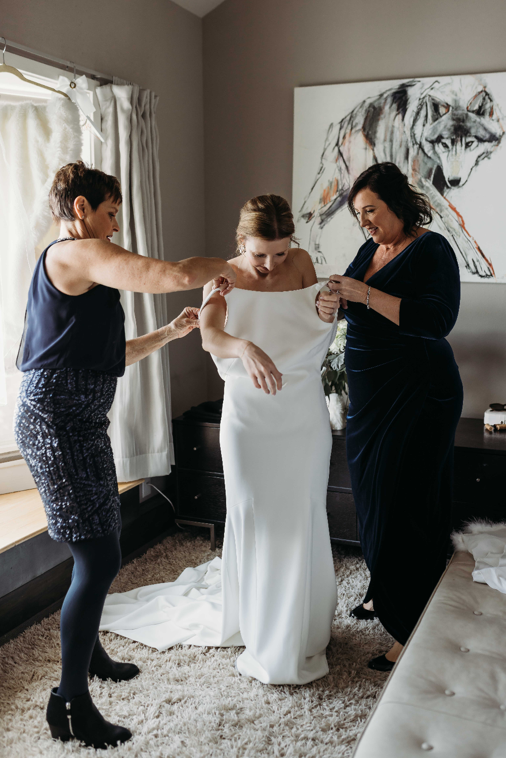 Moms helping bride with wedding dress